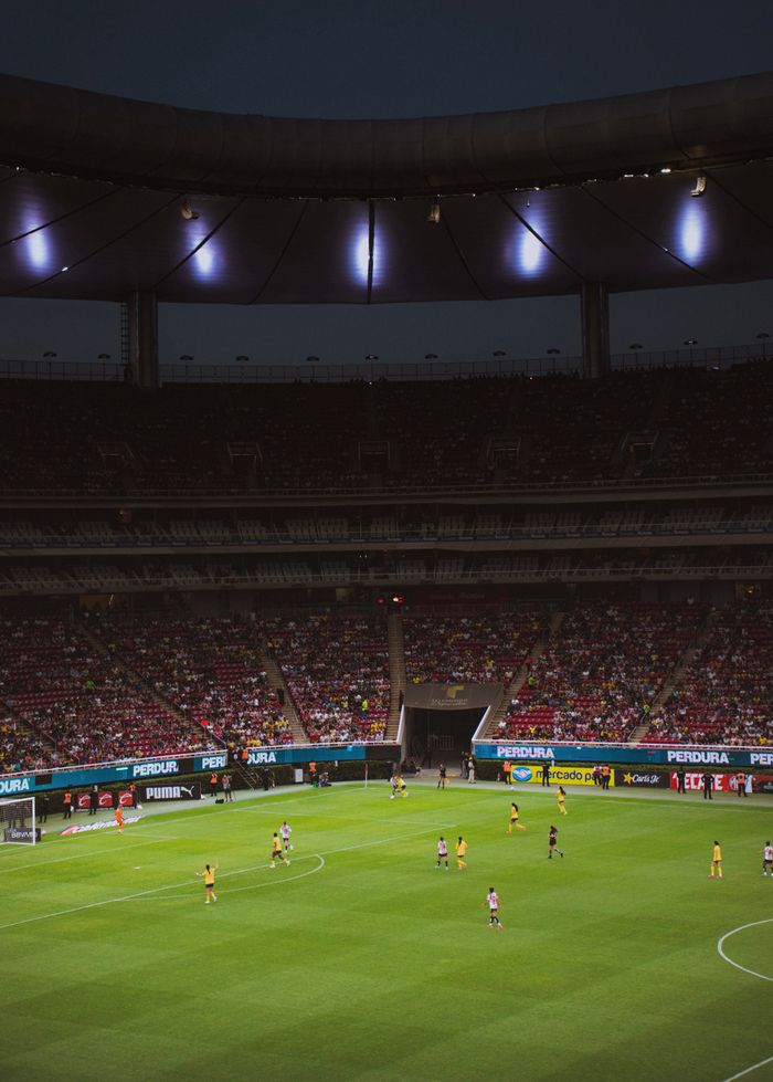 An exciting night football game under bright stadium lights with a large cheering audience.
