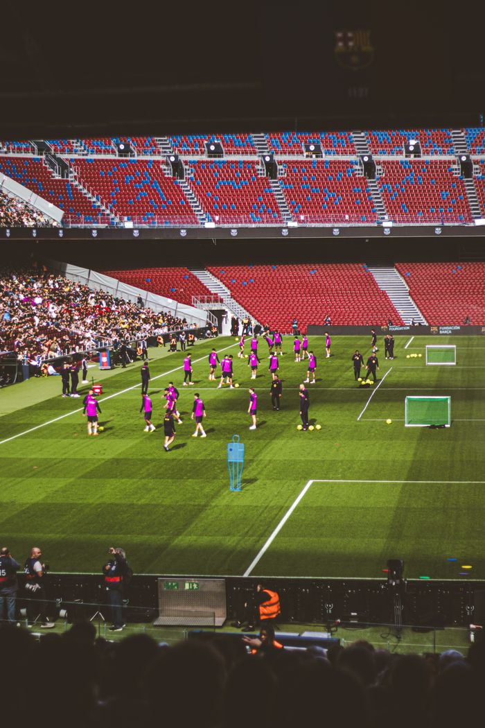 Soccer team players warming up in a large stadium with a crowd watching.