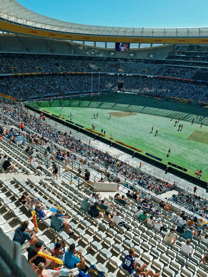 Aerial view of a lively rugby match in a bustling outdoor stadium during the day.