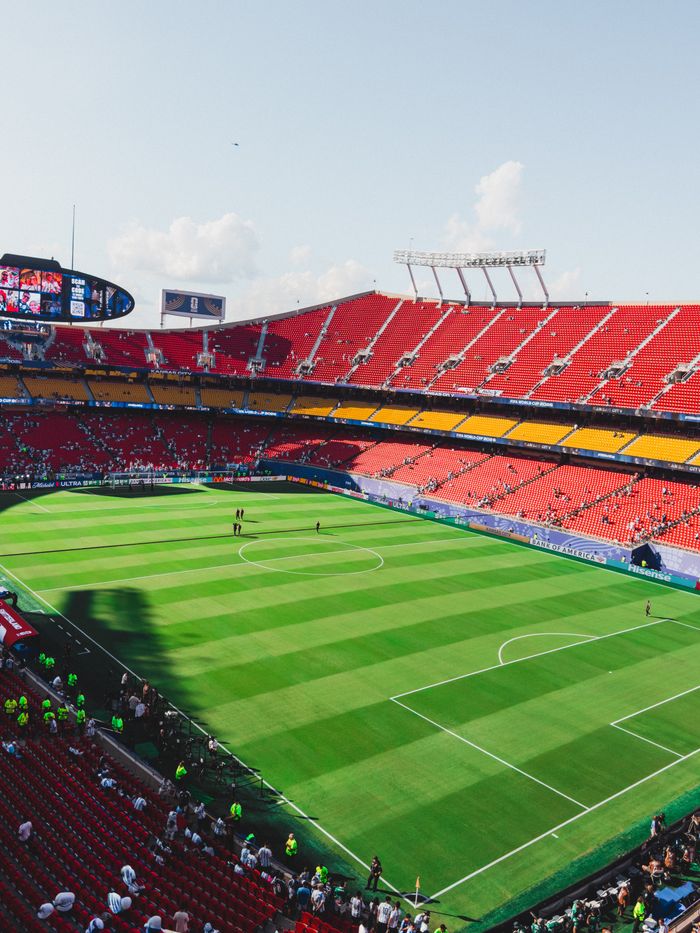 Overhead shot of a colorful soccer stadium filled with fans during daytime.