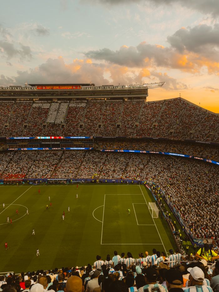 A packed stadium during a dramatic soccer match at sunset, capturing the excitement of the game.